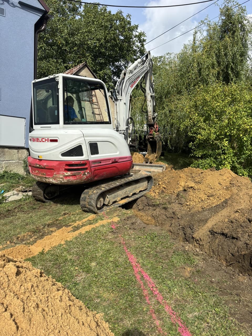 Minibagr kope rýhu pro kanalizační přípojku u rodinného domu ve Staříči